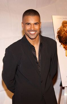 a man in a black suit smiling for the camera