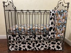 a black and white cow print crib bedding next to a brown wooden floor