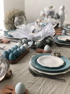 the table is set with blue and white plates, silverware, and wine glasses