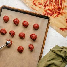 a cookie sheet with red cookies on it and a spatula