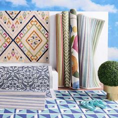 an assortment of colorful fabrics and rugs on display in front of a blue sky