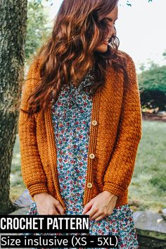 a woman standing in front of a tree wearing an orange cardigan