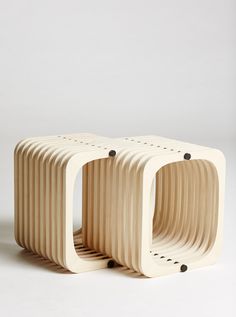 three wooden stools sitting side by side on a white surface with black dots in the middle