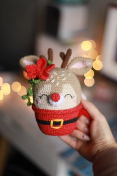 a hand holding a small knitted christmas decoration with reindeer's head and antlers