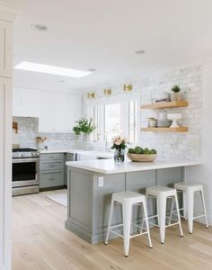 a kitchen with white and gray cabinets, counter tops and stools in front of the island