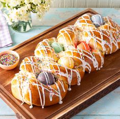 a wooden tray topped with donuts covered in icing and toppings on top of a table