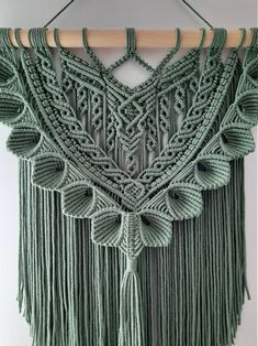 a green macrame wall hanging with tassels