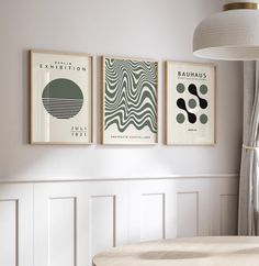 three framed art prints hang on the wall above a round table in a white room