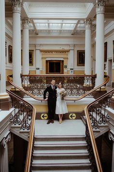 a bride and groom are standing on the stairs in an old building with marble columns