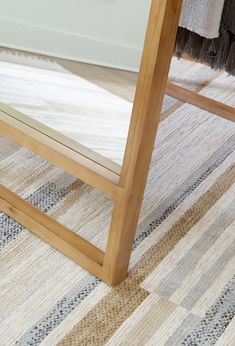 a large mirror sitting on top of a wooden floor next to a white chair and rug