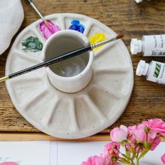 the paintbrushes are next to an empty cup