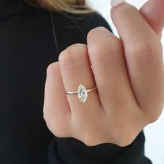 a woman's hand wearing a gold ring with a pear shaped diamond on it