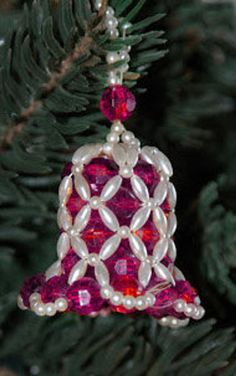 a christmas ornament hanging from a pine tree with red and white beads on it