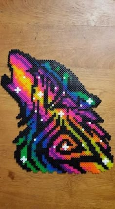 a piece of beaded art that looks like a zebra's head on a wooden surface