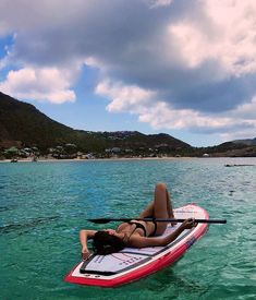 a woman laying on top of a kayak in the ocean