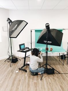 a woman sitting on the floor in front of a camera and lighting equipment set up