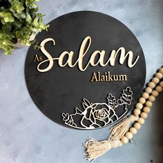 a sign that says salam with flowers and tassels on the table next to it