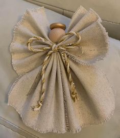 a close up of a decorative object on a couch with white fabric and gold trim