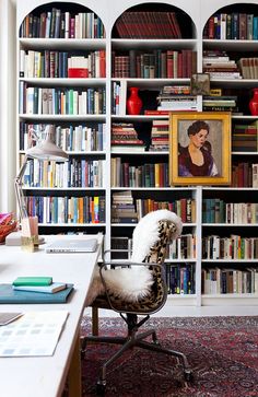 a chair in front of a bookshelf filled with lots of books next to a desk