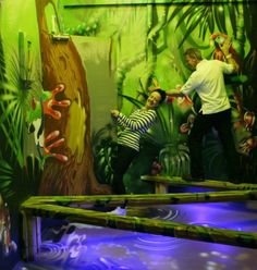 two children are playing on an indoor trampoline course at the zoo with their mother and father