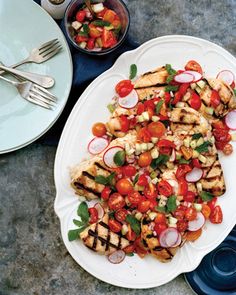 a white plate topped with grilled chicken and veggies next to a fork