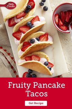 fruity pancake tacos on a cutting board with strawberries and blueberries