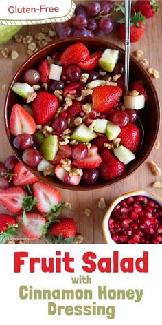 fruit salad with cinnamon honey dressing in a bowl on a wooden table next to grapes and strawberries