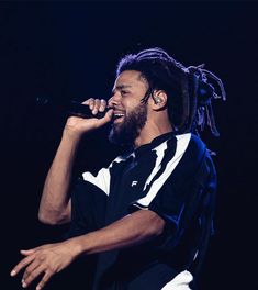 a man with dreadlocks singing into a microphone