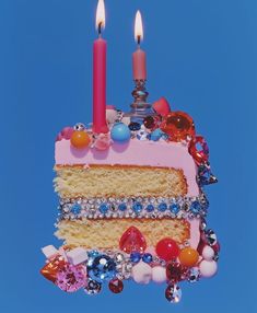 a piece of cake with two candles on it is surrounded by jewels and other decorations