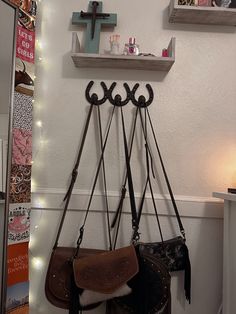 a cross hanging on the wall next to two purses and a mirror with lights around it