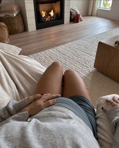 a woman laying on top of a couch next to a fire place