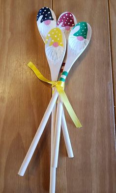 three plastic spoons with different designs on them sitting on top of a wooden table