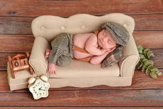 a baby sleeping on top of a couch next to a clock