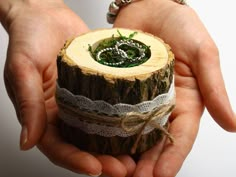 a person holding a piece of wood with lace on it's edges and ring in their hands