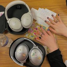 a woman's hands with manicures and headphones on top of a wooden table