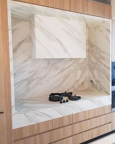 a kitchen with marble counter tops and wooden cabinets in the back wall, along with black appliances