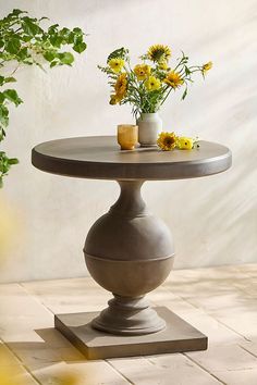 a vase with flowers sitting on top of a table next to a potted plant