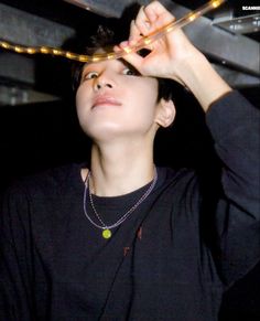 a young man wearing a black shirt and holding a pair of scissors above his head