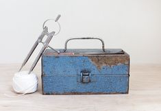 an old toolbox with yarn and scissors on it sitting next to a ball of thread