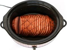 an open crock pot filled with sliced meat on top of a white countertop