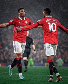 two soccer players are congratulating each other on the field as rain falls over them