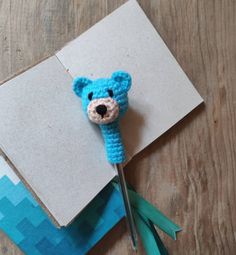 a crocheted blue bear head on top of a piece of paper with scissors