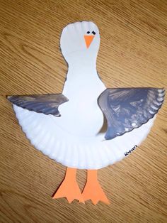 a paper plate shaped like a duck on top of a wooden table with an orange beak