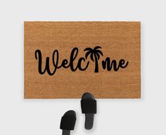 a welcome mat with slippers on it and the word welcome written in black ink