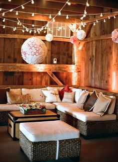 a living room filled with lots of couches and tables covered in pillows next to wooden walls