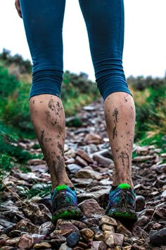 a person standing on top of a rocky trail with mud all over their legs and feet