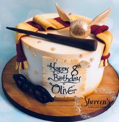 a birthday cake decorated with harry potter's wand, glasses and hat on a wooden platter