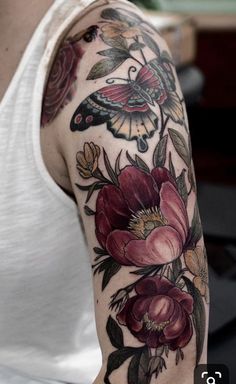 a woman's arm with flowers and butterflies tattooed on her left arm, in white tank top