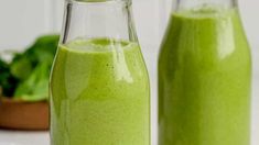 two bottles filled with green smoothie sitting next to each other