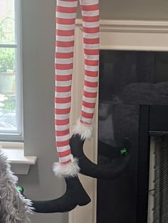 a cat in the hat hanging from a christmas tree with stockings and leggings